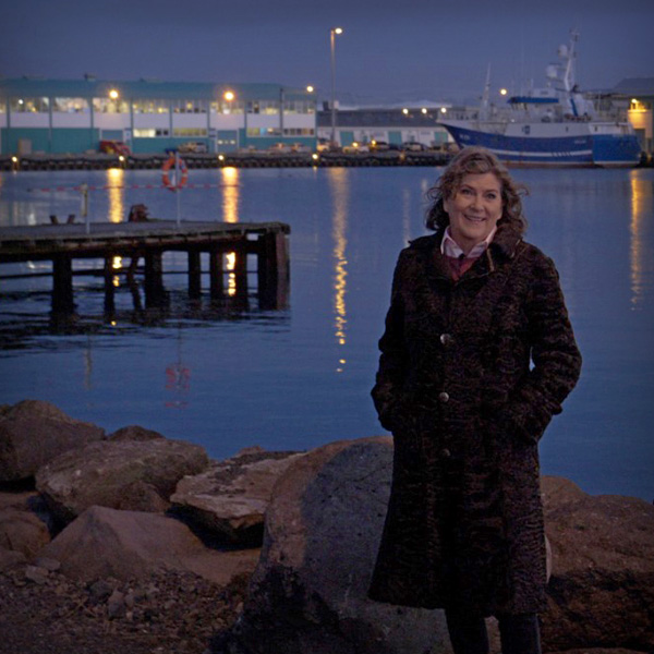 A smiling woman standing at an harbour in a dusk