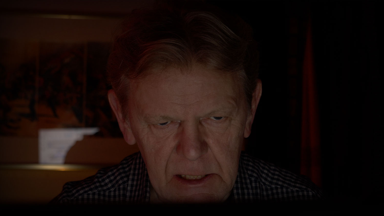 A sombre man looking at a computer screen
