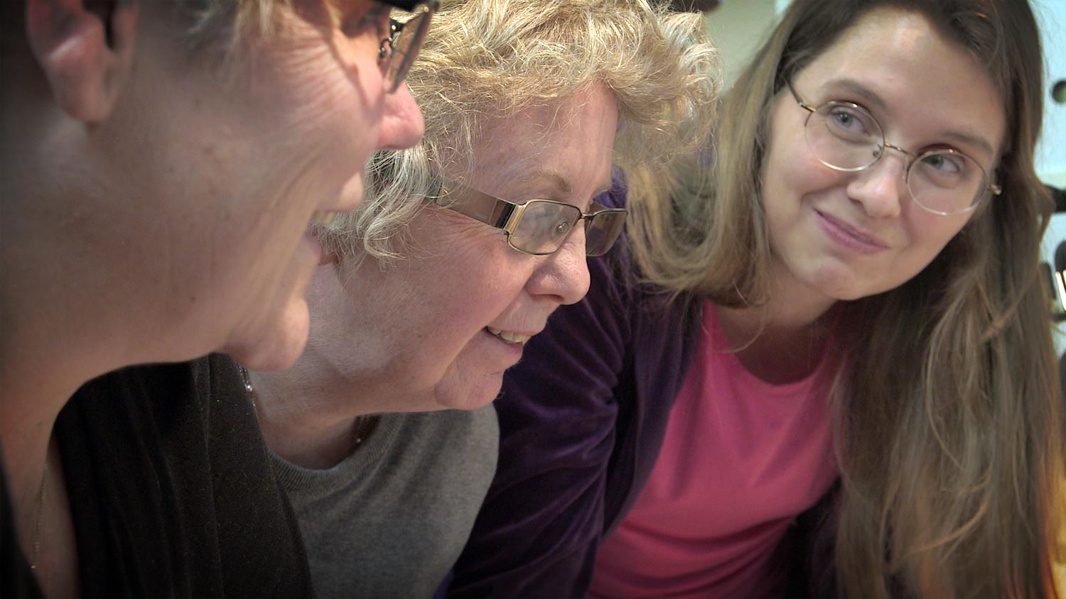 Faces of three women who were intently following a sewing course, but are  now smiling to each other.